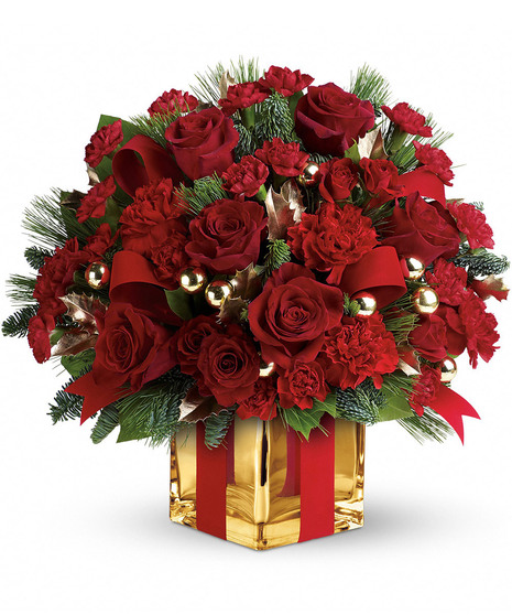 A bouquet of red roses, carnations, and green pine in a gold vase with red ribbon, adorned with gold ornaments and leaves, arranged festively.