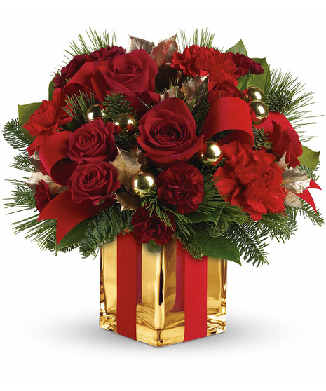 A bouquet of red roses, carnations, and green pine in a gold vase with red ribbon, adorned with gold ornaments and leaves, arranged festively.