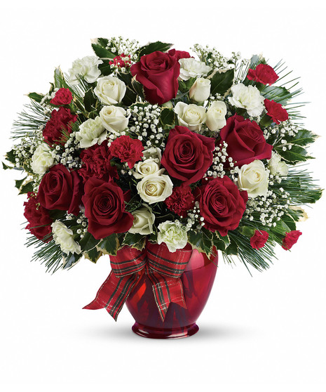 A bouquet of red and white flowers arranged in a red vase, adorned with green leaves and a plaid ribbon, placed against a plain white background.