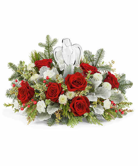 A festive arrangement of red roses, pinecones, and lush greenery sits in a red vase adorned with a cardinal bird design, complemented by white flowers and red berry accents.