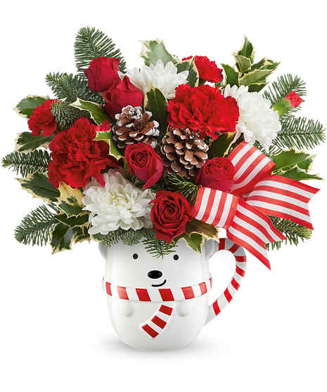 A festive arrangement of red roses, pinecones, and lush greenery sits in a red vase adorned with a cardinal bird design, complemented by white flowers and red berry accents.