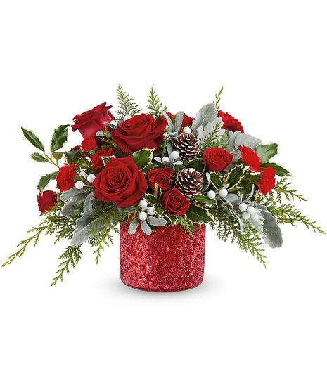 A festive arrangement of red roses, pinecones, and lush greenery sits in a red vase adorned with a cardinal bird design, complemented by white flowers and red berry accents.