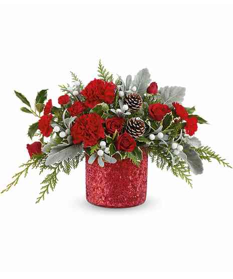A festive arrangement of red roses, pinecones, and lush greenery sits in a red vase adorned with a cardinal bird design, complemented by white flowers and red berry accents.