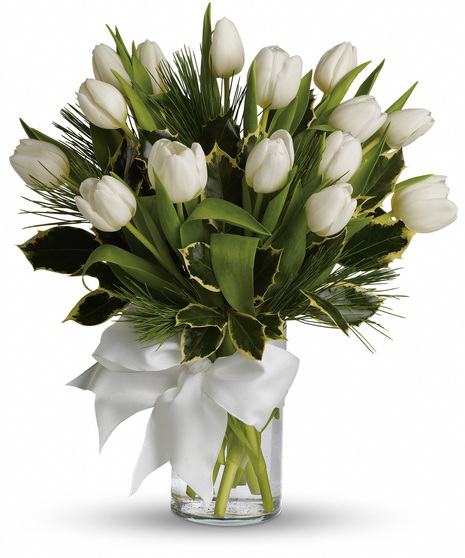 A bouquet of white tulips arranged in a cylindrical glass vase with water, accented by green foliage and adorned with a large white ribbon in a bow.