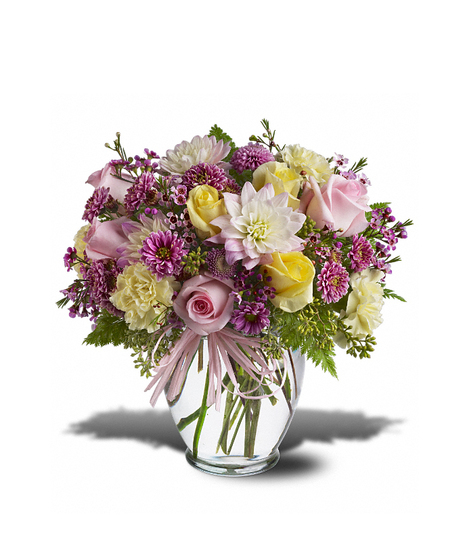 A bouquet of mixed flowers, including pink roses, yellow and white daisies, and purple blossoms, arranged in a clear glass vase with a pink ribbon